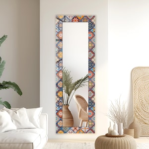 May include: A tall, rectangular wall mirror featuring a decorative frame with a vibrant, multi-coloured geometric tile pattern. The frame displays repeating square motifs in shades of orange, blue, yellow, and white, creating a bold visual border.