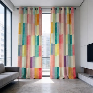 Puede incluir: Un par de cortinas de piso a techo con un patrón de bloques verticales en una paleta de rosa, amarillo, verde azulado, naranja y morado. La tela cuelga de una barra negra mediante ojales metálicos oscuros, creando pliegues uniformes.