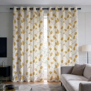 Puede incluir: Un par de cortinas de piso a techo con un patrón repetitivo de hojas de ginkgo amarillas sobre tallos finos, oscuros y sinuosos, sobre un fondo color crema. Las cortinas cuelgan de una barra negra mediante ojales metálicos plateados.