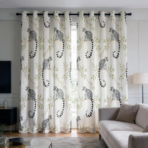 May include: A pair of off-white curtains featuring a repeating pattern of grey lemurs with long, black and white ringed tails perched on thin, light green leafy branches. The curtains are hung on a black rod with silver-toned metal grommets.