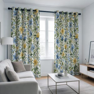 May include: Floral patterned curtains with blue and yellow flowers and green leaves on a white background. The curtains are hanging on a black rod in front of a window. The curtains are in a living room setting.
