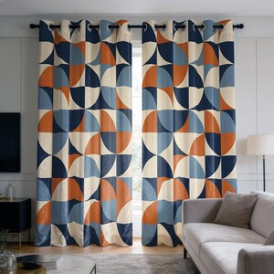 Può includere: Un paio di tende a fantasia con un design geometrico. Le tende presentano un motivo ripetuto di semicerchi e quadrati nei toni blu navy, arancione, azzurro e crema. Le tende sono appese a bastoni neri.