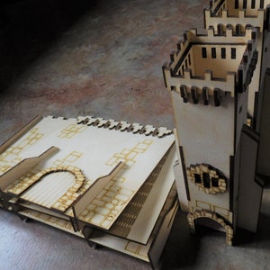 K&ouml;nnte beinhalten: Ein Holzmodell einer Burg mit einem Turm und einem Hof. Der Turm hat ein Zinnendach und ein kleines Fenster. Der Hof besteht aus einer Reihe von Quadraten.
