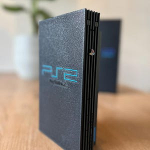 May include: A set of three ceramic mugs with a speckled, cream-colored glaze. Each mug features a different hand-painted floral design in shades of blue, green, and yellow. The mugs have a simple, rounded shape and a comfortable handle.