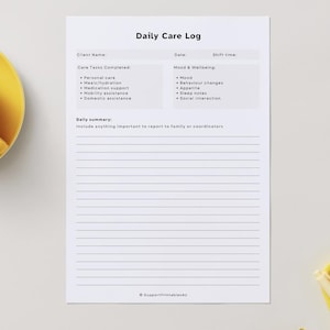 May include: A white Daily Care Log printable sheet with the title at the top. The sheet includes sections for client information, care tasks, mood and wellbeing, and a daily summary. A yellow teacup and saucer are in the upper left corner.
