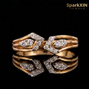 May include: Two gold rings with diamond detailing. Each ring has a geometric design with an oval diamond and smaller diamonds. The rings are shown on a reflective black surface, with the brand name "SparkXIN JEWELS" in the top right corner.