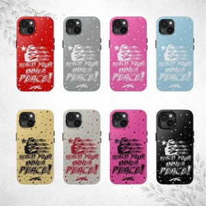 May include: Collection of phone cases in various colors, including red, gray, pink, and blue. Each case features a design with a face, flowing lines, and the text "REACH YOUR INNER PEACE!" in white. The cases have a glossy finish.