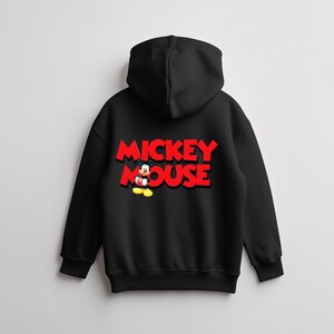 May include: Black hooded sweatshirt featuring the words "MICKEY MOUSE" in red, 3D-style lettering. A cartoon image of Mickey Mouse is positioned below the text. The sweatshirt has a drawstring hood and ribbed cuffs.