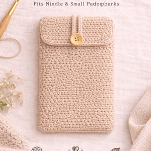 Könnte beinhalten: Handgefertigte Kindle-Hülle aus Häkelarbeit in Beige. Mit Klappenverschluss und Holzknopf. Der Text "Handmade Crochet Kindle Sleeve" ist sichtbar. Hergestellt aus 100% Baumwollgarn und umweltfreundlich.