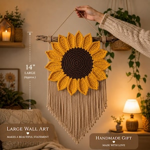 May include: A handmade wall hanging featuring a large, crocheted sunflower with yellow petals and a brown center. The sunflower is approximately 14 inches in diameter and hangs from a wooden branch with macrame detailing. The text reads "LARGE WALL ART" and "HANDMADE GIFT".