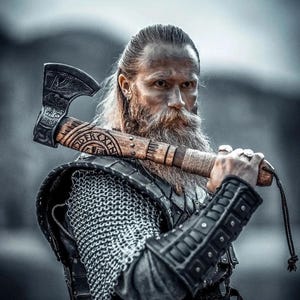 May include: A portrait of a Viking warrior with an axe. The axe features detailed carvings on the wooden handle and blade. The warrior is clad in chainmail armour and leather bracers. The background is blurred, highlighting the warrior and axe.