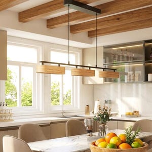 Op de afbeelding: Een moderne keuken met een houten eettafel met marmeren blad, omringd door beige stoelen. Boven hangt een zwarte en houten hanglamp. Een houten kom gevuld met fruit staat op de tafel en voegt kleur toe.