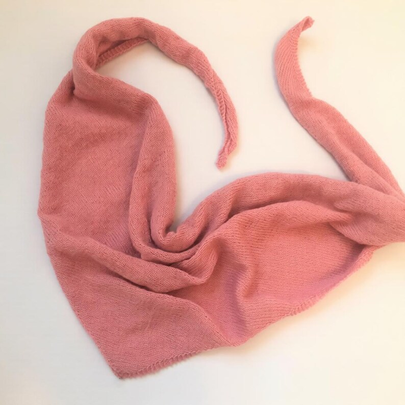 Pode incluir: Cachecol de malha rosa empoeirado. O cachecol est&aacute; dobrado e drapeado, com duas pontas longas e pontiagudas. A textura de malha &eacute; vis&iacute;vel, sugerindo um material quente e aconchegante. Ideal para o inverno.