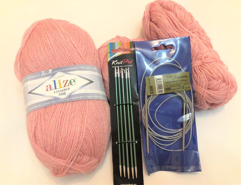 Pode incluir: Uma cole&ccedil;&atilde;o de materiais de tric&ocirc; rosa, incluindo dois novelos de l&atilde;, um conjunto de agulhas de tric&ocirc; verdes e um conjunto de agulhas de tric&ocirc; circulares. A l&atilde; &eacute; rotulada como "Alize Lanagold 800".