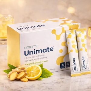 May include: A box of Unicity Unimate yerba mate drink mix with two packets, a glass of drink, a sliced lemon, ginger, and a gold watch. The box and packets have the Unimate logo and text.
