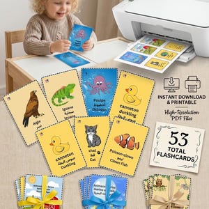May include: A set of 53 printable educational flashcards featuring colourful illustrations of animals with their names in multiple languages. The cards are displayed in stacks tied with ribbons, alongside individual cards showing an eagle, iguana, octopus, duckling, cat, and clown fish.