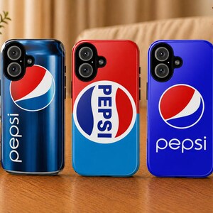 Puede incluir: Tres fundas para teléfono con el logotipo de Pepsi. La funda de la izquierda es azul y tiene forma de lata de Pepsi. La funda del medio es roja y azul con la palabra "PEPSI". La funda de la derecha es azul con el logotipo de Pepsi y la palabra "pepsi".