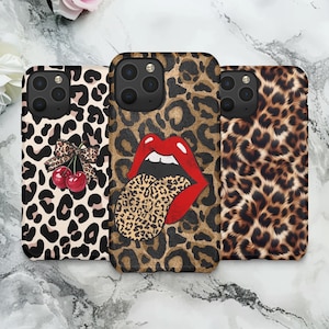 May include: Three phone cases with leopard print designs. One case features a bow and cherries, another has red lips and a leopard tongue, and the third has a simple leopard pattern. The cases are black and brown.