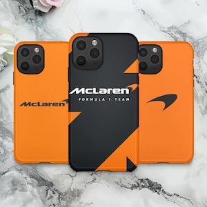 May include: Three orange and black phone cases featuring the McLaren Formula 1 Team logo. The cases are arranged side by side, with the central case black and the others orange. The McLaren logo and text are visible.