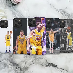 May include: A collection of phone cases featuring basketball players in yellow and purple uniforms. The cases display action shots of players with the number 77, set against various backgrounds, including a white case and a case with a purple and black design.