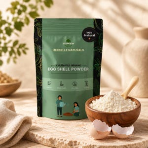 Puede incluir: Una bolsa verde Herbelle Naturals de polvo de cáscara de huevo orgánico cultivado con un sello 100% natural. La etiqueta muestra ilustraciones de personas jardineras, iconos de salud y texto. Un cuenco de madera con polvo blanco está al lado.
