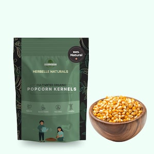 Puede incluir: Una bolsa verde de Herbelle Naturals Cultivated Organic Popcorn Kernels, con un cuenco de madera de granos de palomitas de maíz a la derecha. La bolsa tiene las palabras "100% Natural" e ilustraciones de personas jardinería.