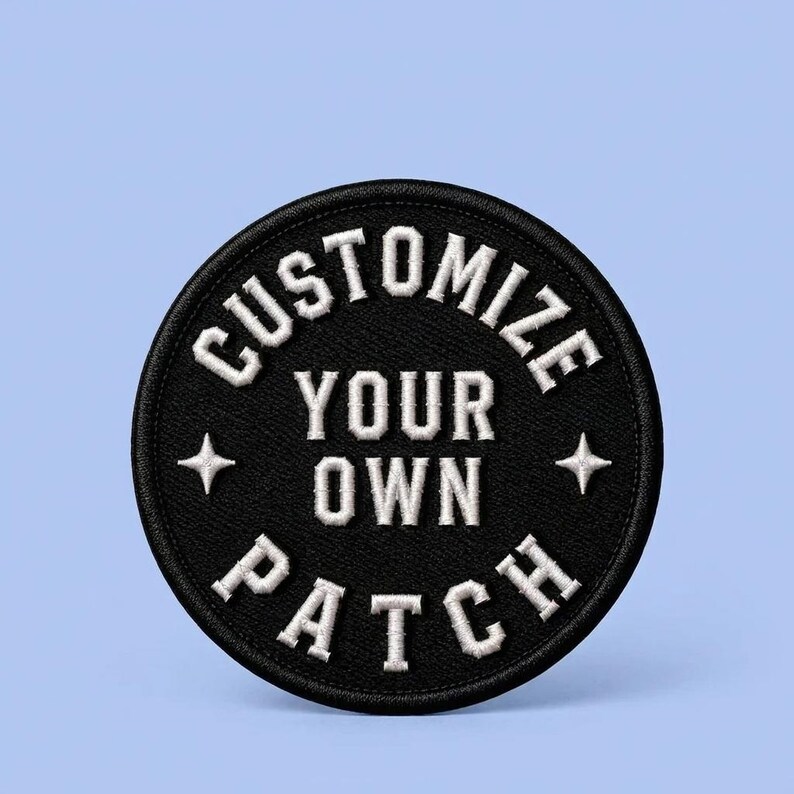 K&ouml;nnte beinhalten: Ein kreisf&ouml;rmiger, schwarz bestickter Aufn&auml;her mit wei&szlig;em, gesticktem Text, der in fetter Schrift CUSTOMIZE YOUR OWN PATCH lautet. Das Design enth&auml;lt zwei kleine vierzackige Sternsymbole links und rechts vom zentralen Text.