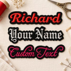 May include: Three custom embroidered name patches on a fabric surface. The top patch features the red text "Richard" on a black background. The middle patch displays the white text "Your Name" in a gothic font. The bottom patch shows pink text "Custom Text" in a cursive script.