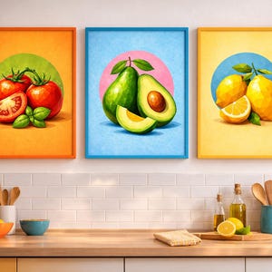 May include: Three framed art prints featuring colorful illustrations of produce. One shows tomatoes, another avocados, and the last lemons. Each image is set against a contrasting background color and framed in a matching color.