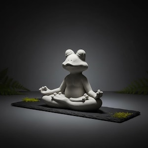 Puede incluir: Una estatua de rana gris claro en una postura de yoga sentado, con las manos en un gesto meditativo. La rana está sobre una estera rectangular negra con acentos de musgo verde. El fondo es un degradado gris oscuro.