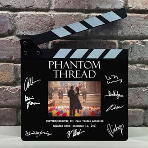 May include: A black film clapperboard featuring the title PHANTOM THREAD in white text, a central scene of a couple dancing amidst colorful balloons, and the text WRITTEN/DIRECTED BY: Paul Thomas Anderson and RELEASE DATE: December 11, 2017.