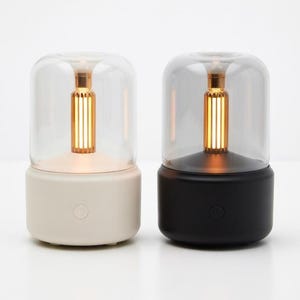 May include: A set of three ceramic mugs with a speckled, cream-colored glaze. Each mug features a different hand-painted design: a blue and green leaf, a yellow flower, and a red berry. The mugs have a simple, rounded shape and a comfortable handle.