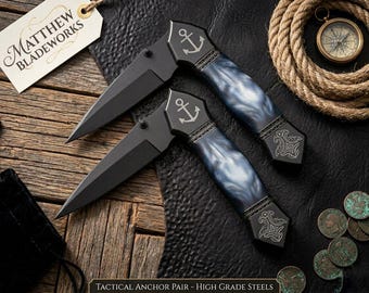 Navaja táctica plegable con ancla náutica, mango de resina azul con diseño de remolino y hoja negra.