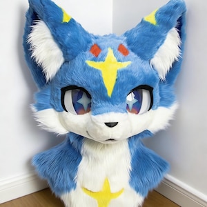 以下が含まれることがあります： 大きな、詳細な目を備えた、青と白の毛皮のキツネの頭。キツネは額と耳に黄色の星のアクセントがあります。毛皮は鮮やかな青色で、顔と胸の周りに白いアクセントがあります。目は星の模様です。