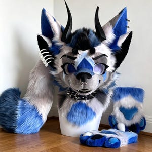 May include: A furry costume set featuring a wolf-like head, tail, paws, and feet. The head has black horns, a nose ring, and a spiked collar. The fur is primarily blue, gray, and white. The tail is long and fluffy, and the paws and feet are detailed.