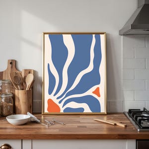 May include: A rectangular wall art print in a thin gold frame featuring an abstract design with organic, flowing shapes in blue, cream, and orange. The composition consists of vertical blue and cream wave-like forms with two solid orange accents.