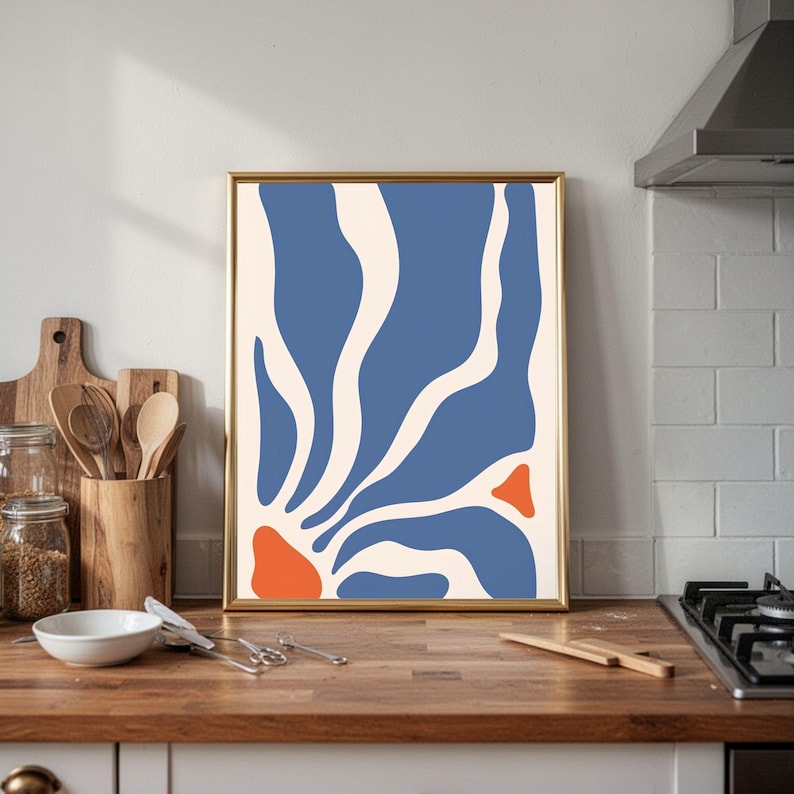 May include: A rectangular wall art print in a thin gold frame featuring an abstract design with organic, flowing shapes in blue, cream, and orange. The composition consists of vertical blue and cream wave-like forms with two solid orange accents.