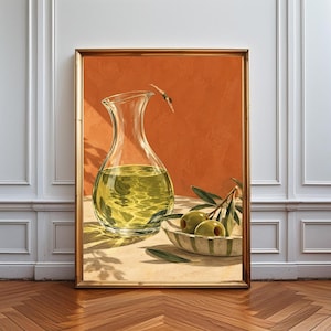 May include: A framed wall art print featuring a clear glass carafe filled with golden olive oil, positioned next to a small bowl containing two green olives on a branch. A tiny figure is shown diving into the oil against a solid orange background.