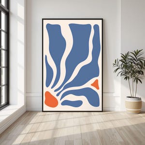 May include: A vertical rectangular wall art print in a black frame featuring an abstract composition of organic blue shapes radiating from the bottom left corner against a cream background, with two distinct orange shapes interspersed.