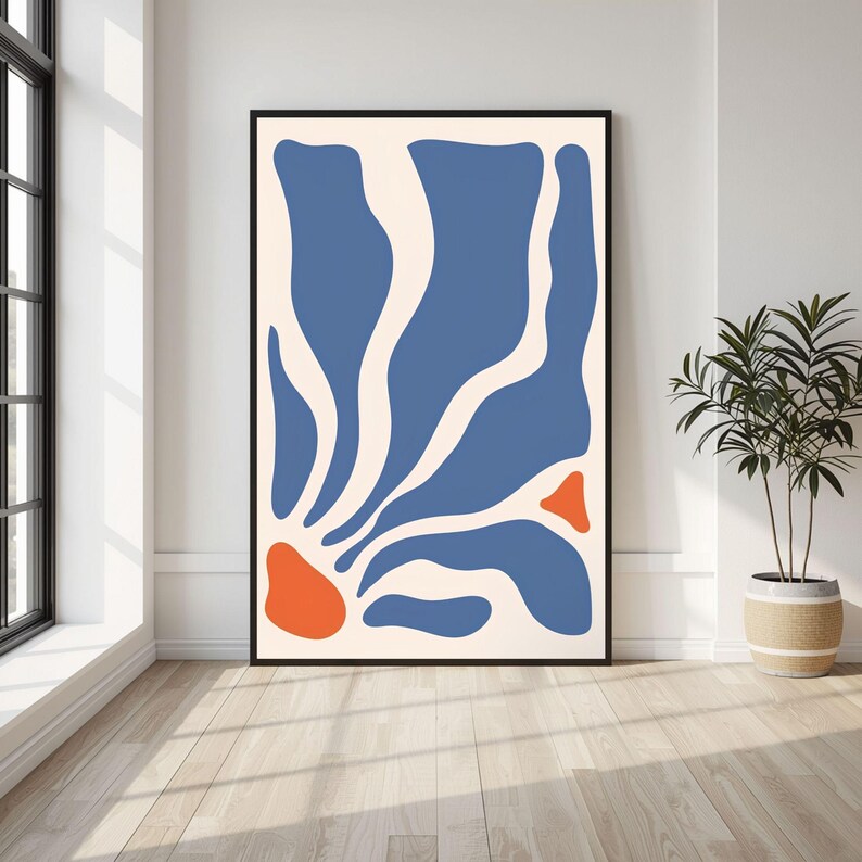 May include: A vertical rectangular wall art print in a black frame featuring an abstract composition of organic blue shapes radiating from the bottom left corner against a cream background, with two distinct orange shapes interspersed.