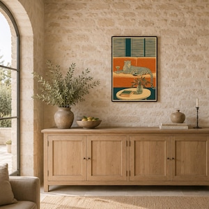 Peut inclure: Une impression d'art mural rectangulaire dans un cadre noir repr&eacute;sentant une illustration stylis&eacute;e d'un l&eacute;opard allong&eacute; sur un canap&eacute; orange avec un verre &agrave; martini, devant des stores vert fonc&eacute;, avec une table, une plante et un livre.
