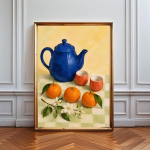 Puede incluir: Un cuadro de naturaleza muerta enmarcado que presenta una tetera azul vibrante, dos tazas pequeñas de color naranja y tres naranjas frescas con hojas verdes y flores blancas dispuestas sobre un mantel de cuadros verde claro y blanco.