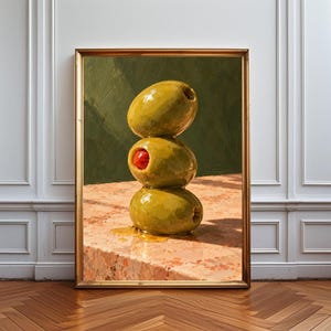 May include: A framed oil painting depicting a vertical stack of three green olives on a speckled pink marble surface. The middle olive features a bright red pimento centre. The background is a dark, textured olive green with visible brushstrokes.
