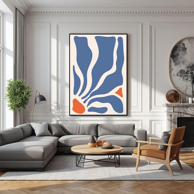 May include: A rectangular wall art print featuring a cream background with organic, flowing blue shapes and two smaller, solid orange shapes arranged in a vertical composition, enclosed within a thin black frame hanging on a white wall.