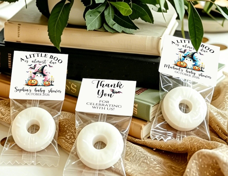 May include: Three clear plastic bags containing white ring-shaped candies, each sealed with a white paper topper. Two toppers feature a ghost in a witch hat with pumpkins and the text A LITTLE BOO is almost due. One topper says THANK YOU.