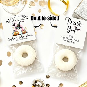 May include: Two white ring-shaped candies in clear plastic bags with square paper toppers. The left topper says A LITTLE BOO is almost due, Sophia's baby shower, OCTOBER 2026 with a ghost, pumpkins, and bats. The right topper says Thank You.