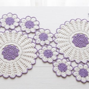 Peut inclure: Chemin de table et dessous de verre assortis en crochet faits à la main. Le chemin de table présente un motif floral avec des couleurs blanches et lavande. Le chemin de table mesure environ 120 cm de long.