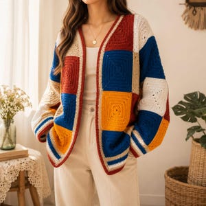 K&ouml;nnte beinhalten: Eine lang&auml;rmelige Strickjacke aus geh&auml;kelten Granny Squares im Patchwork-Muster. Das Kleidungsst&uuml;ck besticht durch eine lebendige Farbpalette aus Dunkelrot, leuchtendem Blau, Senfgelb und Creme, mit V-Ausschnitt und offenem Vorderteil.