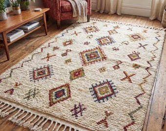 May include: A rectangular area rug with a cream-colored base featuring a textured, shaggy pile. The rug is decorated with a repeating pattern of colorful geometric shapes, including diamonds and crosses in red, blue, yellow, and green, finished with knotted fringe.
