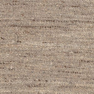 A very close-up, detailed view of the beige flatweave rug's texture, showing individual woven fibers.